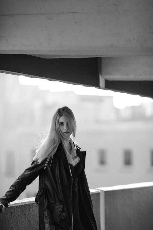 Young Woman in Black Coat Posing on Balcony