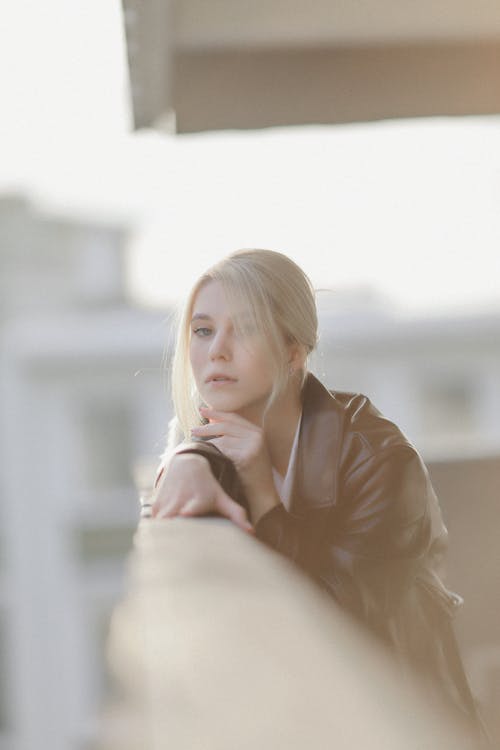  Young Woman in a Leather Coat Leaning Against the Railing