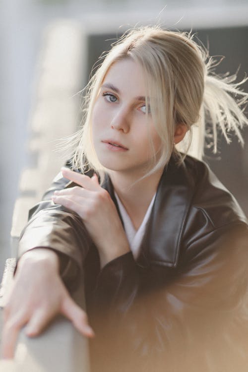 Young Woman in a Leather Coat Crouching by the Railing