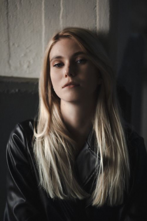 Free Charming portrait of a young woman in a leather coat with natural light indoors. Stock Photo