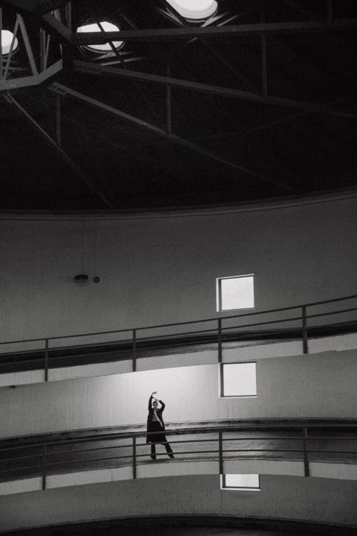 Free Monochrome image of a woman posing in a spiral parking garage with striking architecture. Stock Photo