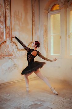 Striking pose of a ballerina in a black dress performing in an artistic, rustic studio.