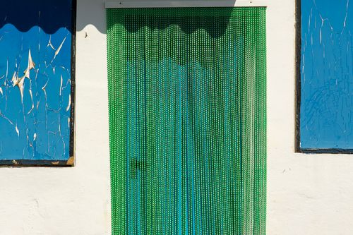 Free Artistic facade featuring a green beaded curtain and textured blue panels. Perfect for decoration concepts. Stock Photo