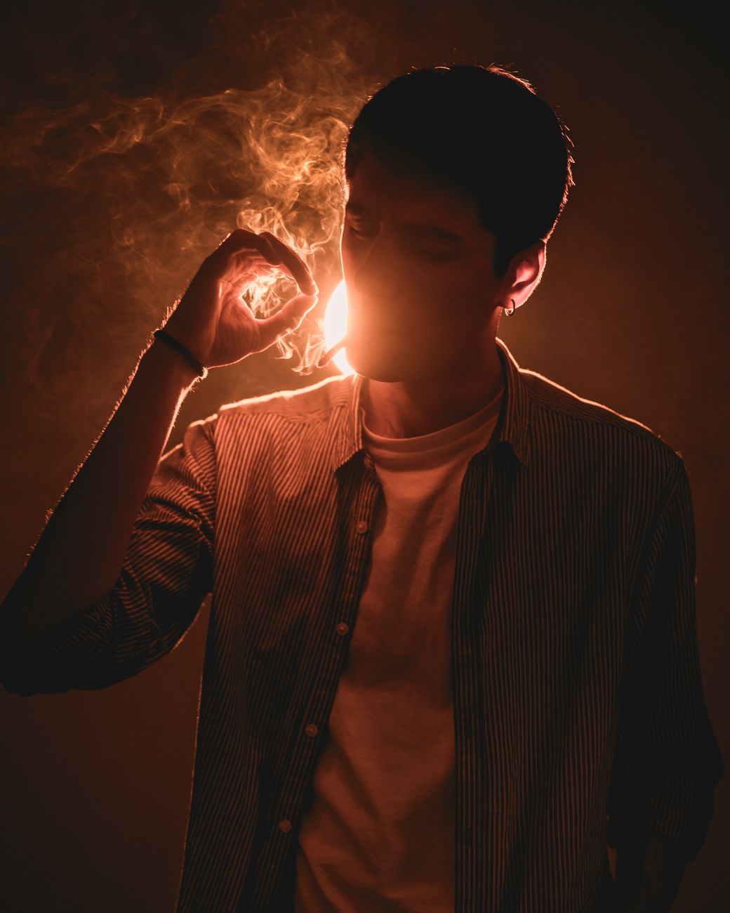 Silhouette of a man smoking with dramatic backlighting creating a mysterious atmosphere.