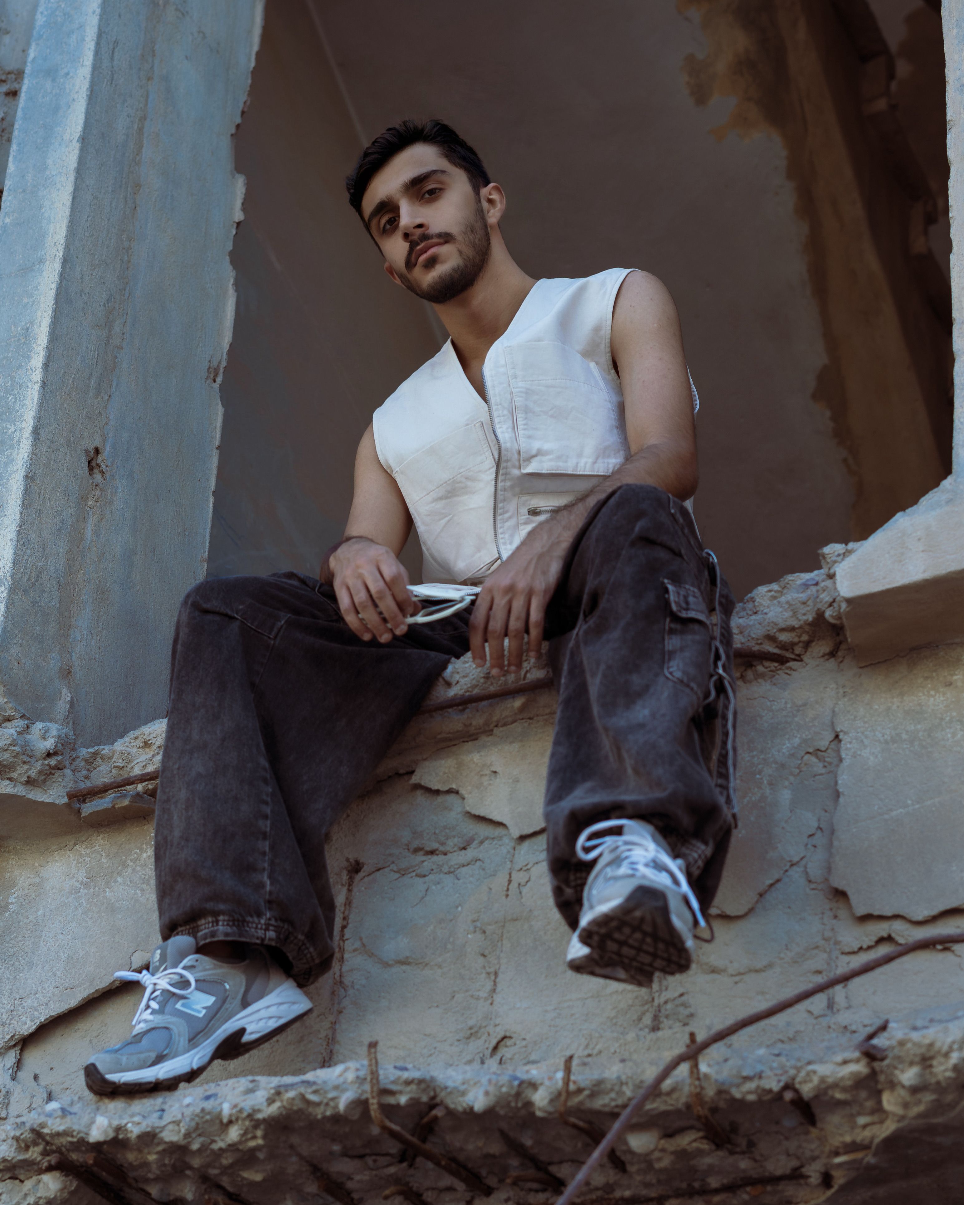 Man sitting in urban ruins wearing modern casual fashion, capturing the essence of street style.