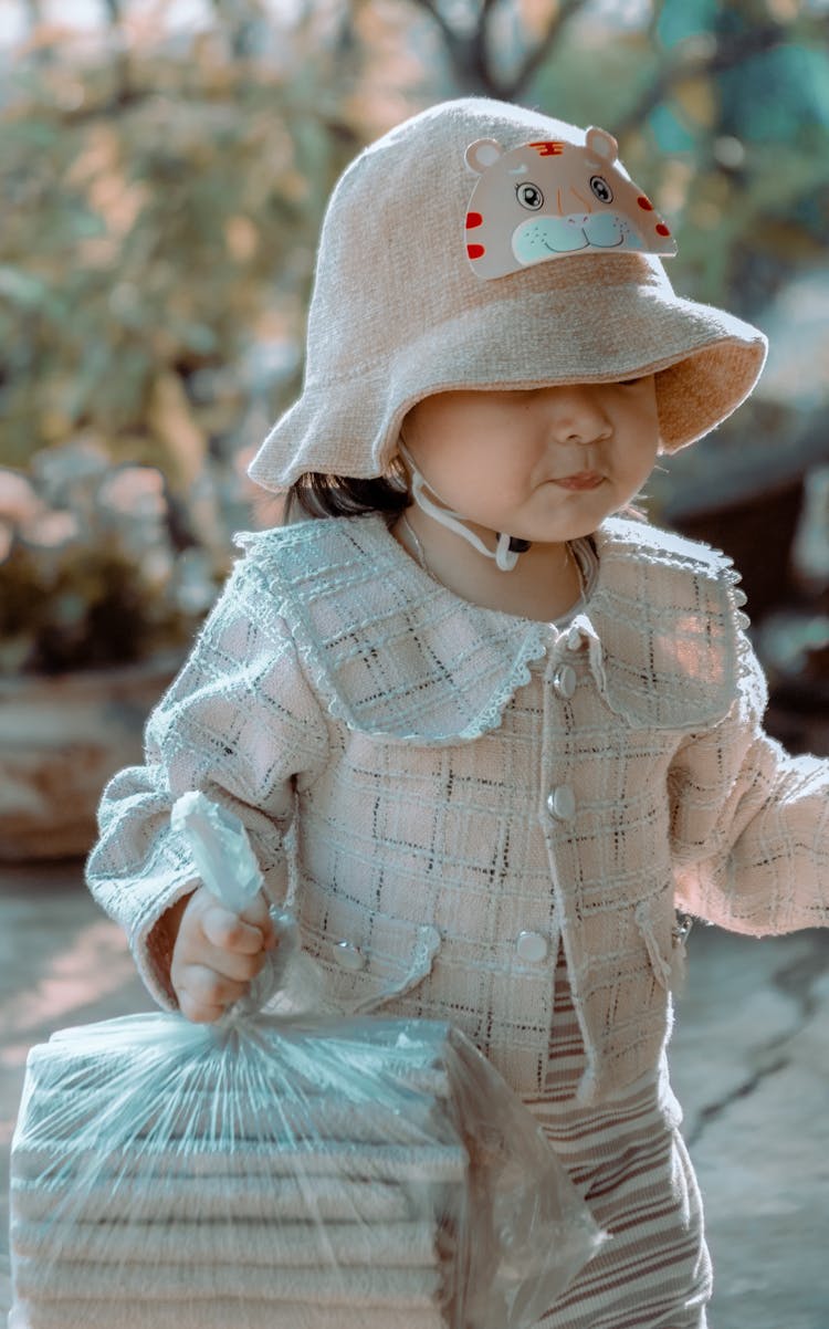 Little Girl In A Hat Carrying A Bag