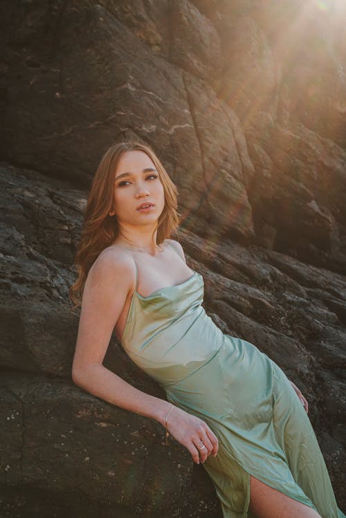 Woman in Satin Gown Lying on Rocks