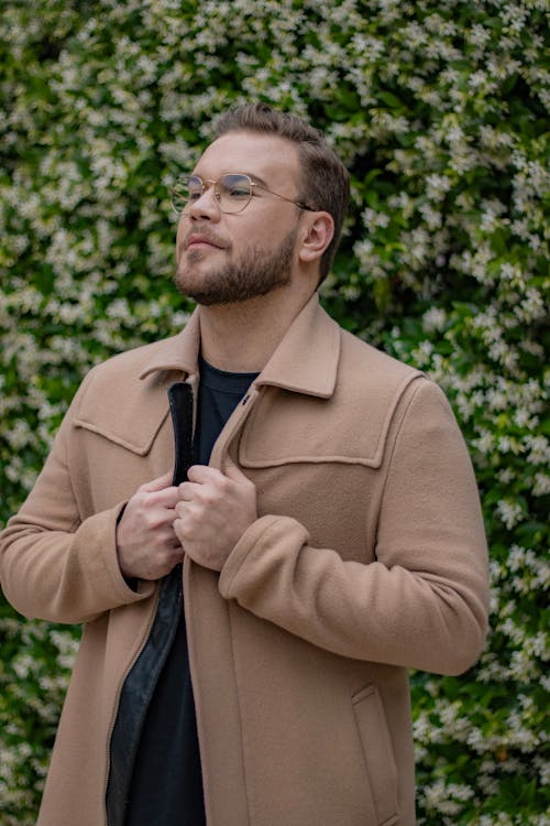 Model in a Wool and Cashmere Beige Jacket in Front of a Flowering Hedge