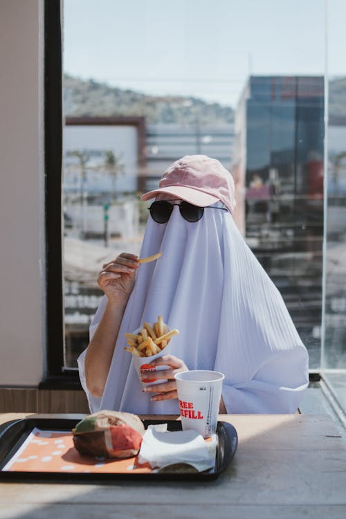 Person Wearing a Sheet and Eating Fast Food 