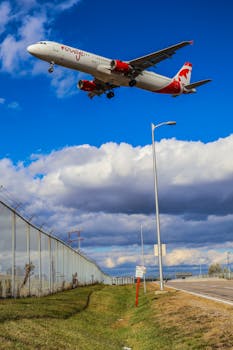 Airplane descending over a city landscape in Mississauga with bright clouds and open sky.
