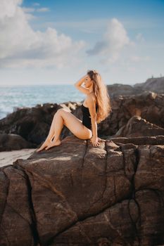 A woman in swimwear sitting on rocks by the sea in Salvador, Brazil, during a sunny day.
