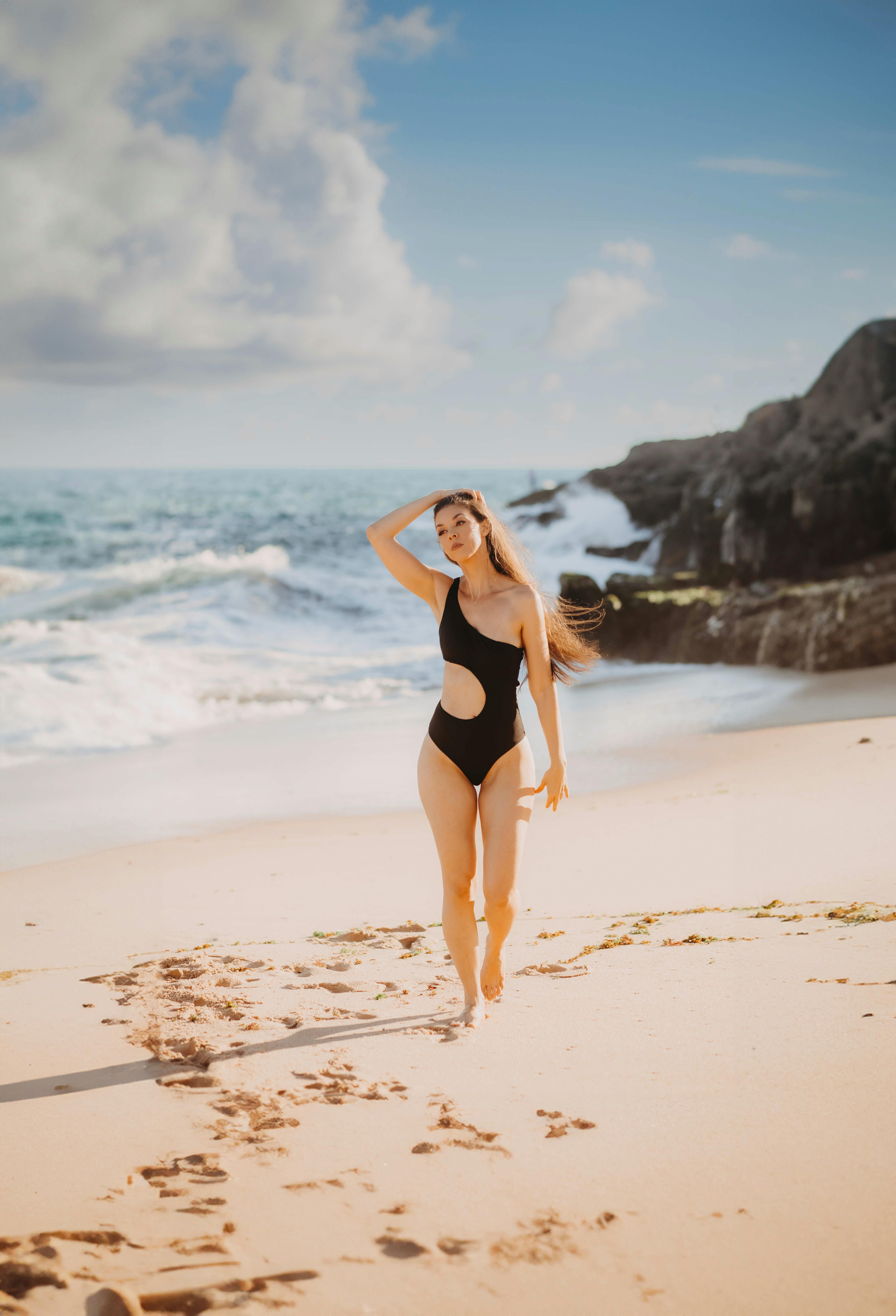 在阳光明媚的日子里，模特穿着黑色泳衣在萨尔瓦多的沙滩上散步