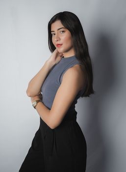 Portrait of a young woman in stylish clothes posing elegantly in a studio setting.