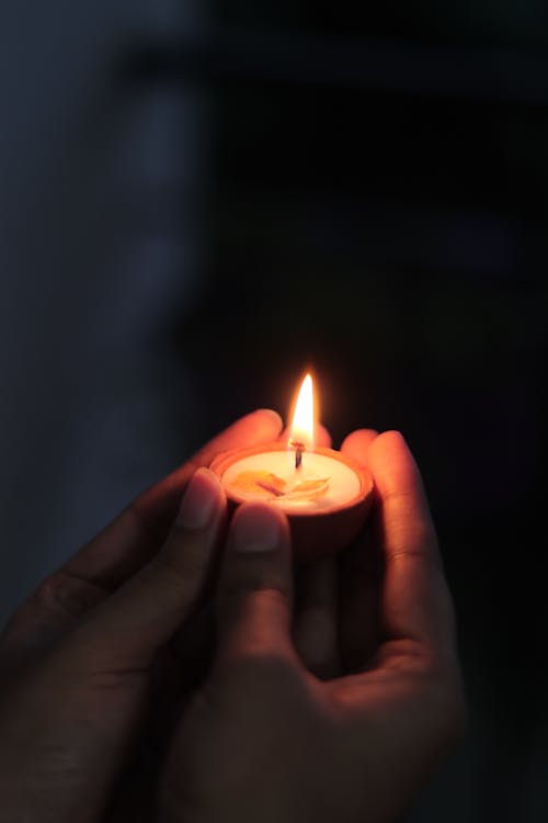 Hands Holding a Candle in the Dark