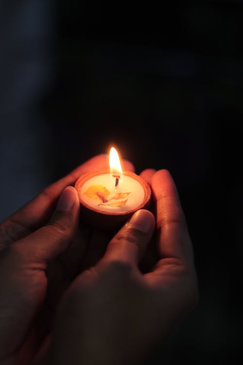Close-up on Hands Holding Lit Tealight Candle