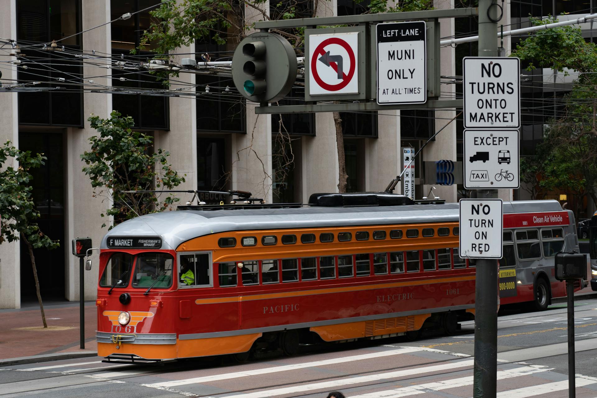 A classic red tram travels through an urban street with traffic signs in downtown.