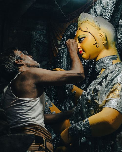 Free A craftsman meticulously paints a Durga idol in a traditional Kolkata workshop, highlighting religious artistry. Stock Photo