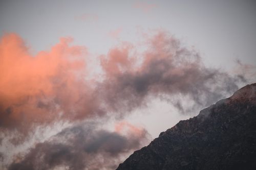 Free Breathtaking view of a mountain peak silhouetted against a vibrant sunset sky with colorful clouds. Stock Photo