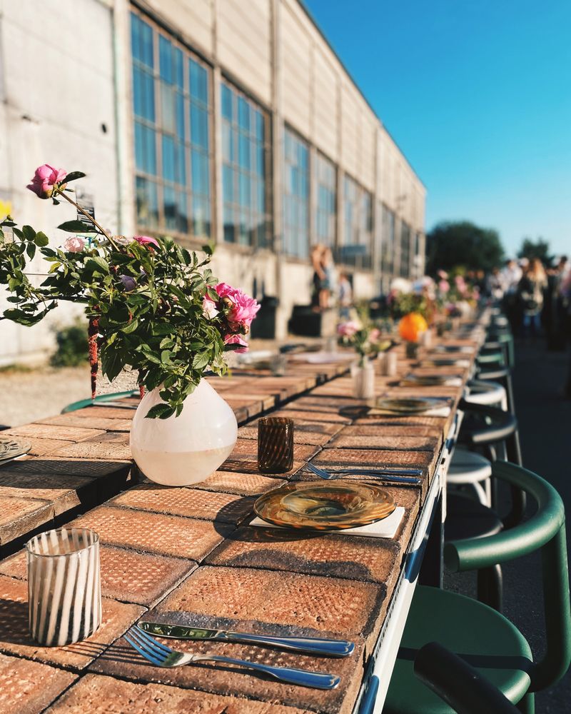 Lange gedeckte Tafel im Freien mit Blumenvasen