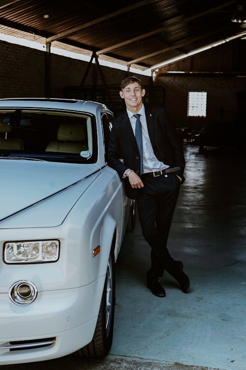 Smiling Man in Suit Standing by Luxury Car