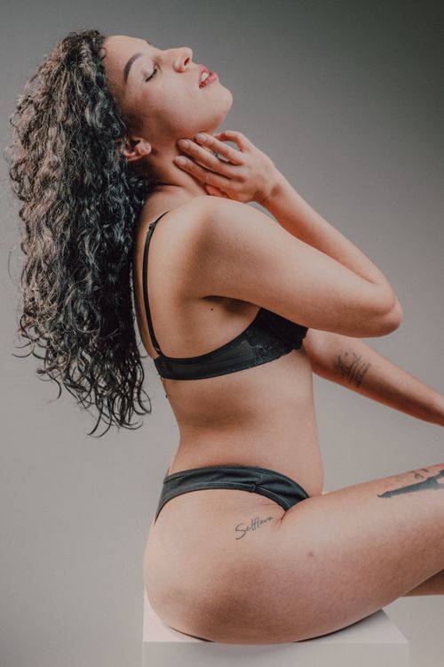 Free Sophisticated brunette model posing gracefully in black lingerie against a soft background. Stock Photo