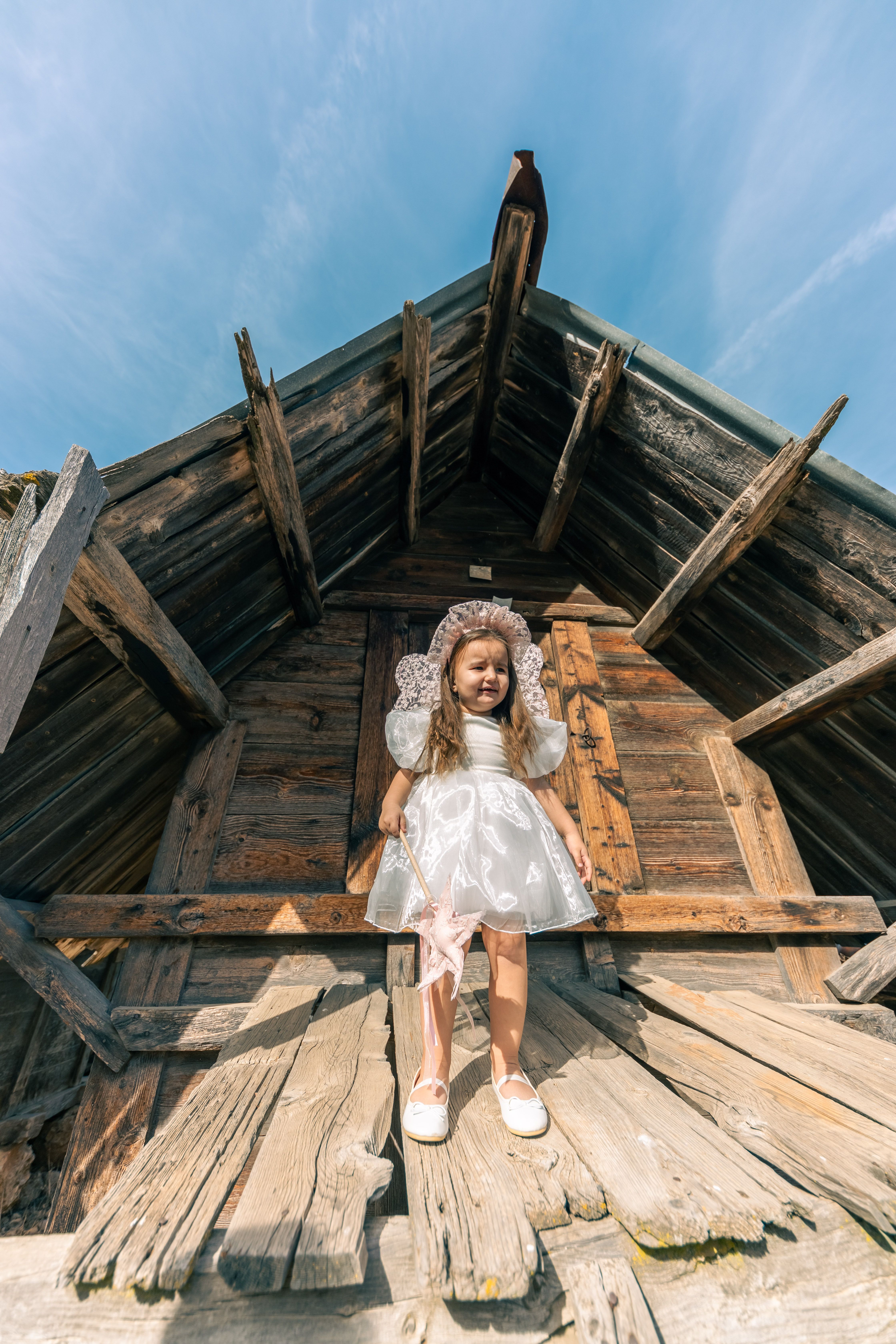 Girl in a Dress Sitting by a Wooden Cabin · Free Stock Photo