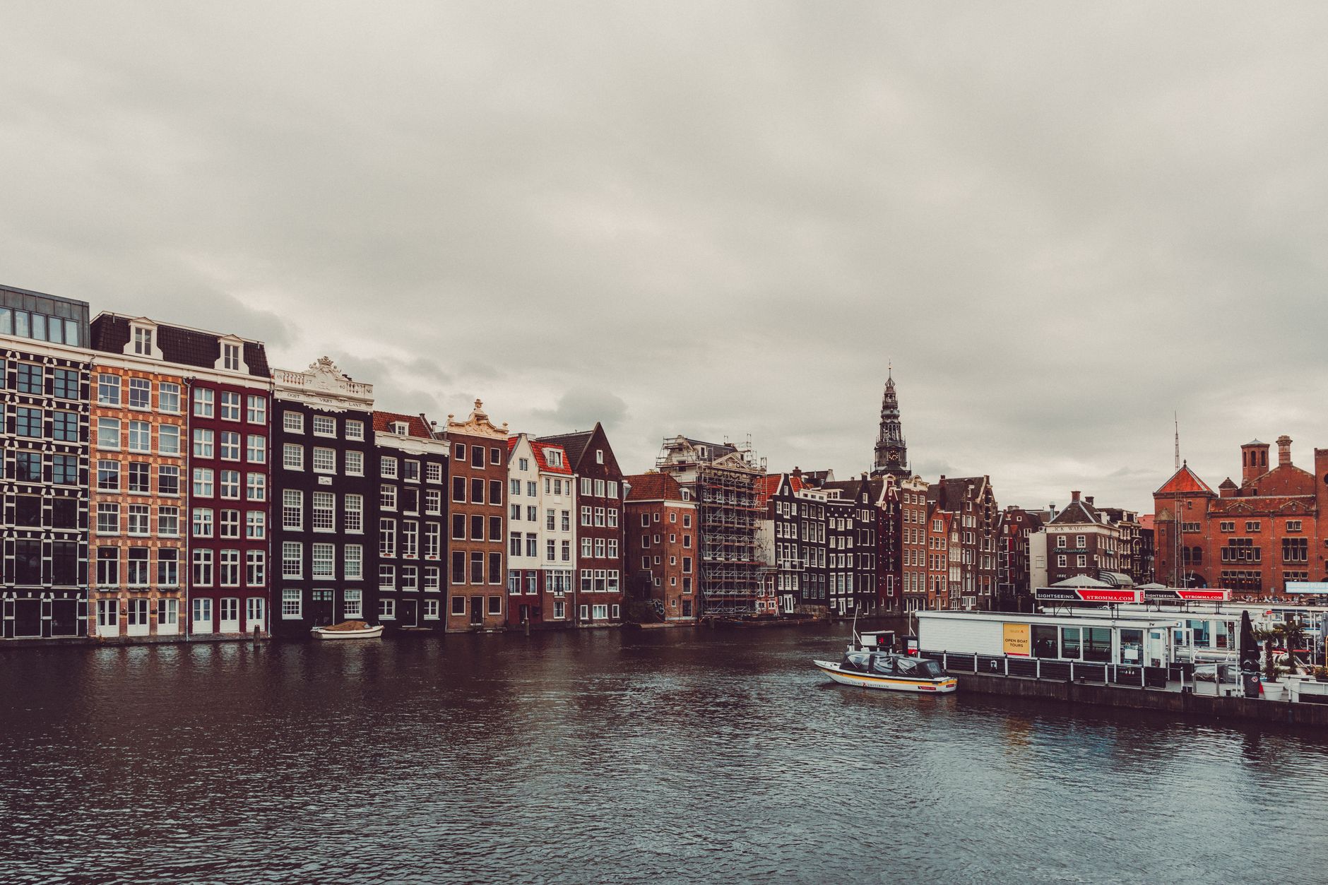 Charming Amsterdam canal and traditional houses with cloudy sky.