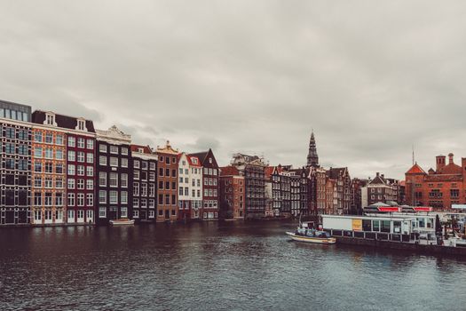 Charming Amsterdam canal and traditional houses with cloudy sky.