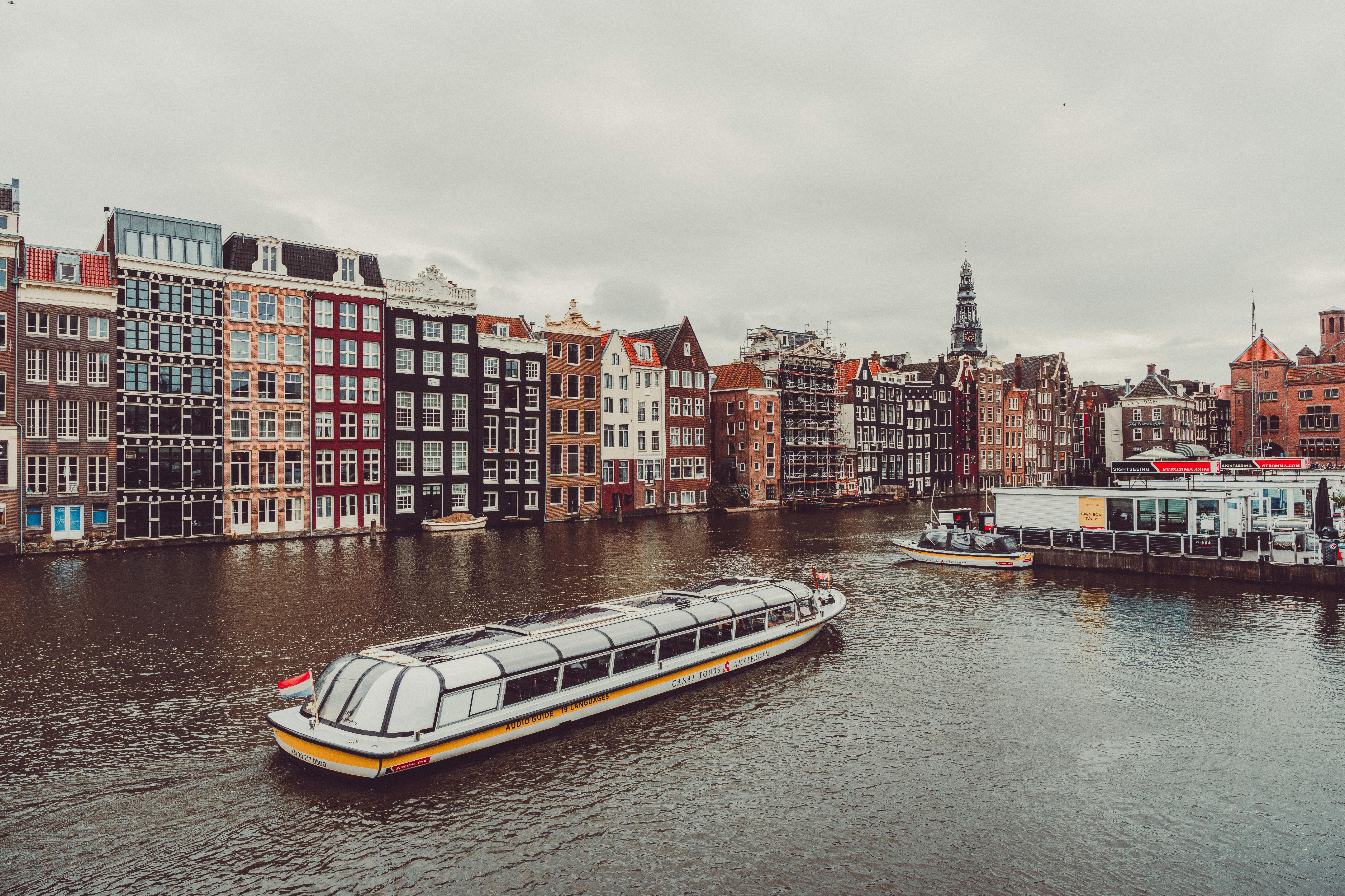 Picturesque Amsterdam canal scene with tour boats and historic architecture — UNESCO-listed 17th-century canals