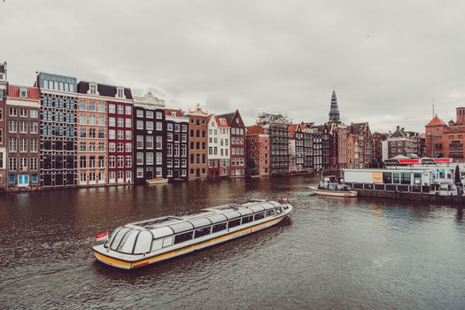 Picturesque Amsterdam canal scene featuring tour boats and historic architecture, ideal for travel content.