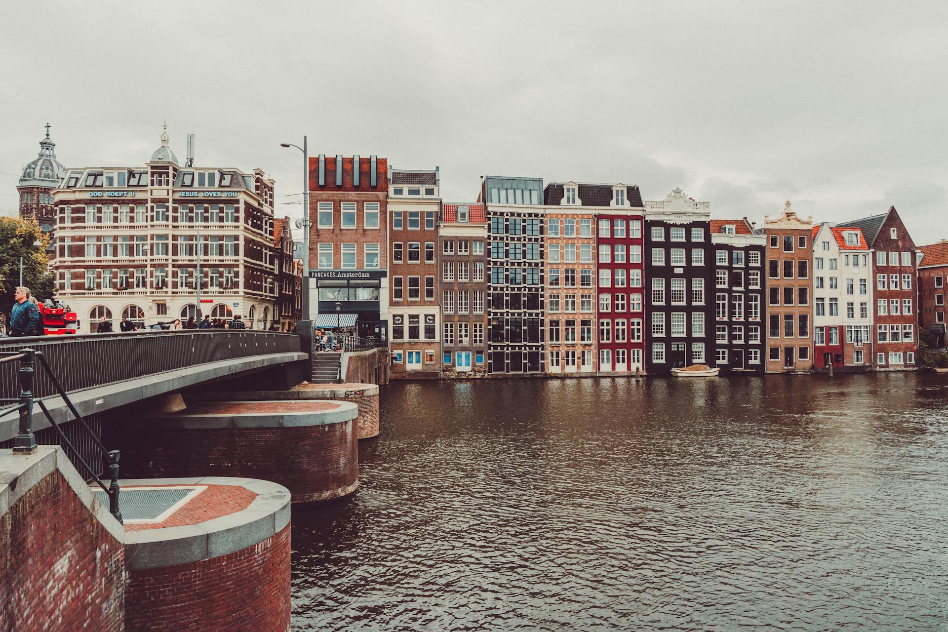 Beautiful view of colorful canal houses along the river in Amsterdam, capturing traditional Dutch architecture and water reflections.