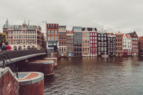 Free Beautiful view of colorful canal houses along the river in Amsterdam, capturing traditional Dutch architecture and water reflections. Stock Photo