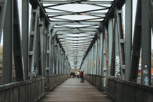 Free A perspective shot of people walking on a steel bridge with graffiti, showcasing urban architecture. Stock Photo
