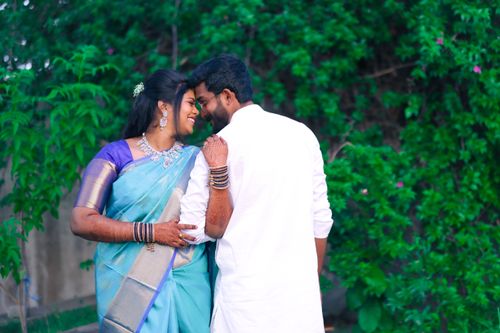 Free Smiling Indian couple in traditional attire embracing amidst lush greenery, showcasing love and tradition. Stock Photo