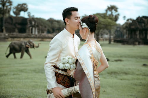 Bride and Groom in Traditional Cambodian Wedding Clothing Standing on a Field 