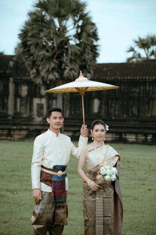 Traditionally Dressed Young Couple Standing Under an Umbrella