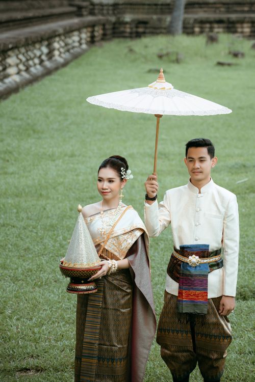 Free Traditional Asian couple in wedding attire posing outdoors, showcasing cultural clothing. Stock Photo