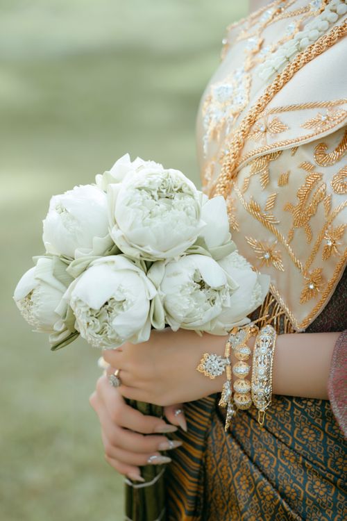 Free Close-up of a woman's hands holding a white peony bouquet wearing traditional attire. Stock Photo