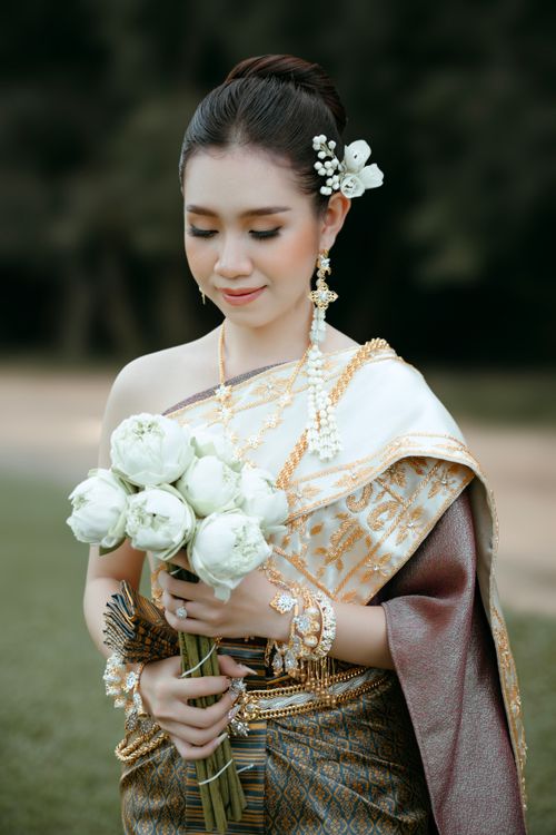 Free Asian woman in traditional Thai dress holding flowers, exuding elegance and grace. Stock Photo