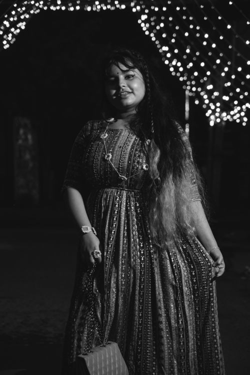 Free Black and white portrait of a woman in traditional clothing at night, featuring illuminated background lights. Stock Photo