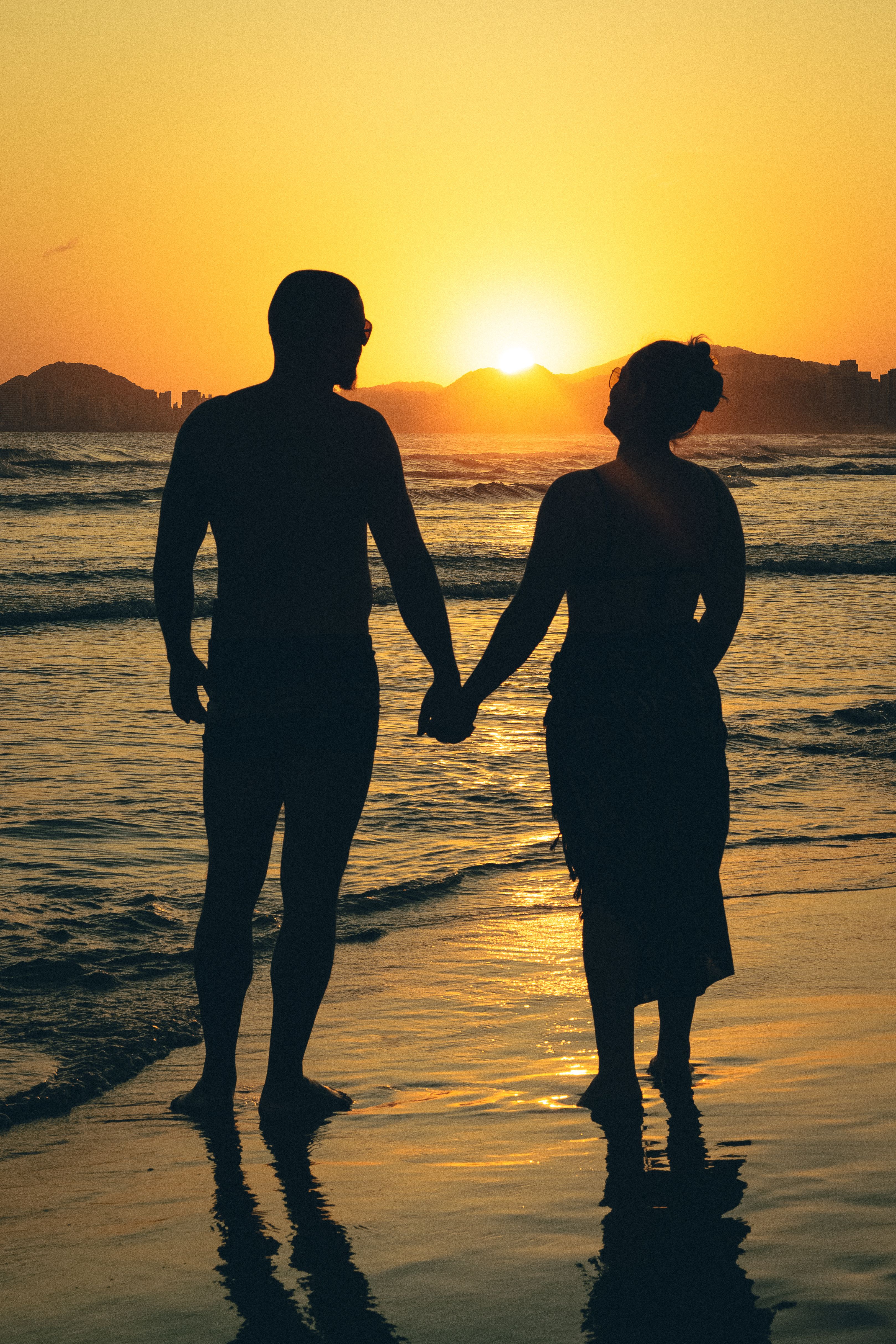 Silhouette of Couple Holding Hands on Beach at Sunset · Free Stock Photo