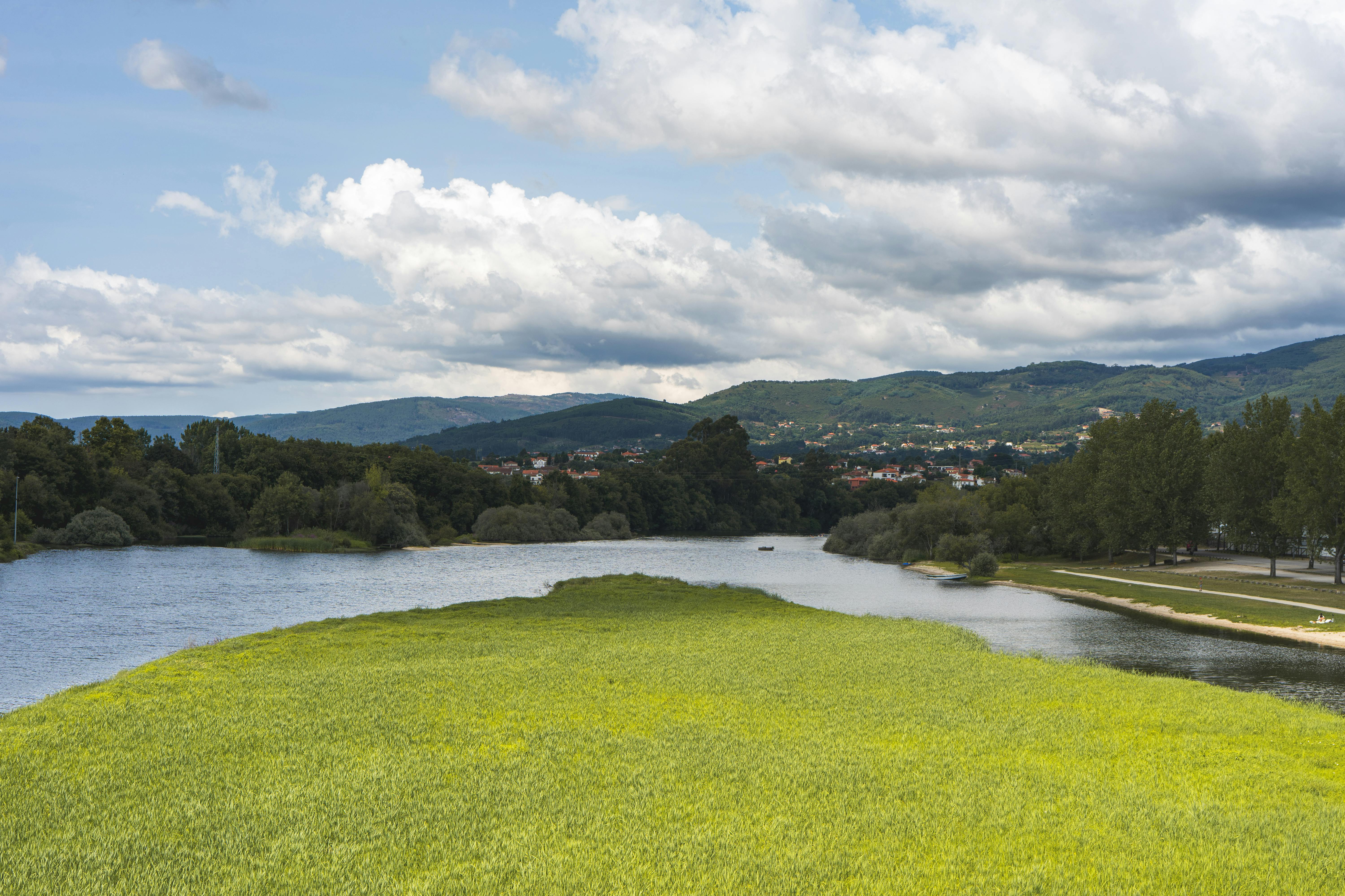 Idyllic landscape view of a river flowing through Ponte de Lima, Portugal, with lush greenery and mountains.