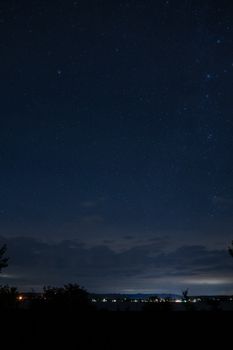 A breathtaking night sky filled with stars above Maple Springs, MN, showcasing illuminated town lights and a serene landscape.