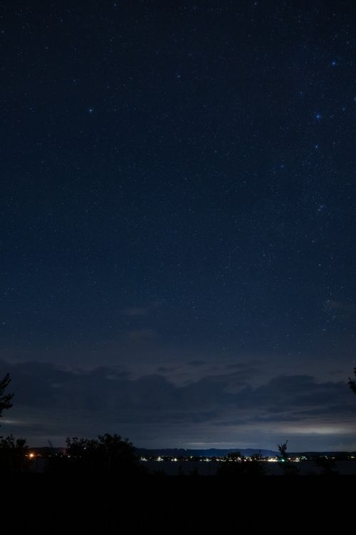 Free A breathtaking night sky filled with stars above Maple Springs, MN, showcasing illuminated town lights and a serene landscape. Stock Photo