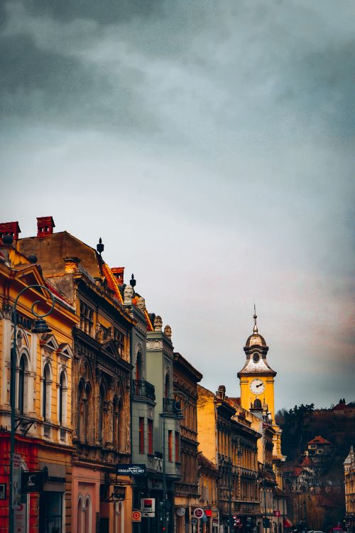 Free Charming old European street with clock tower under overcast sky. Urban architecture. Stock Photo