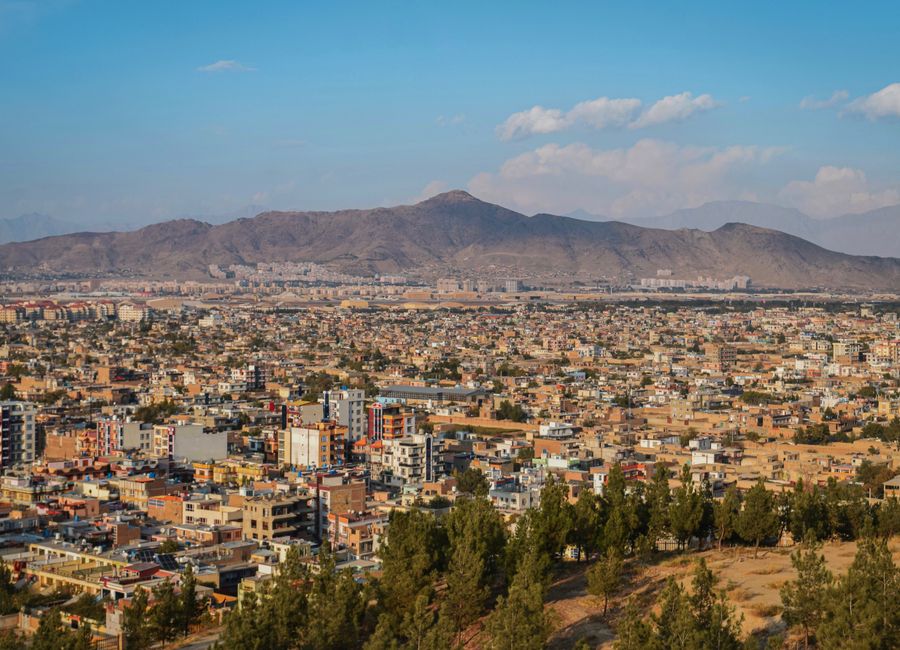 Aerial cityscape of Kabul, Afghanistan with mountains in the background.
