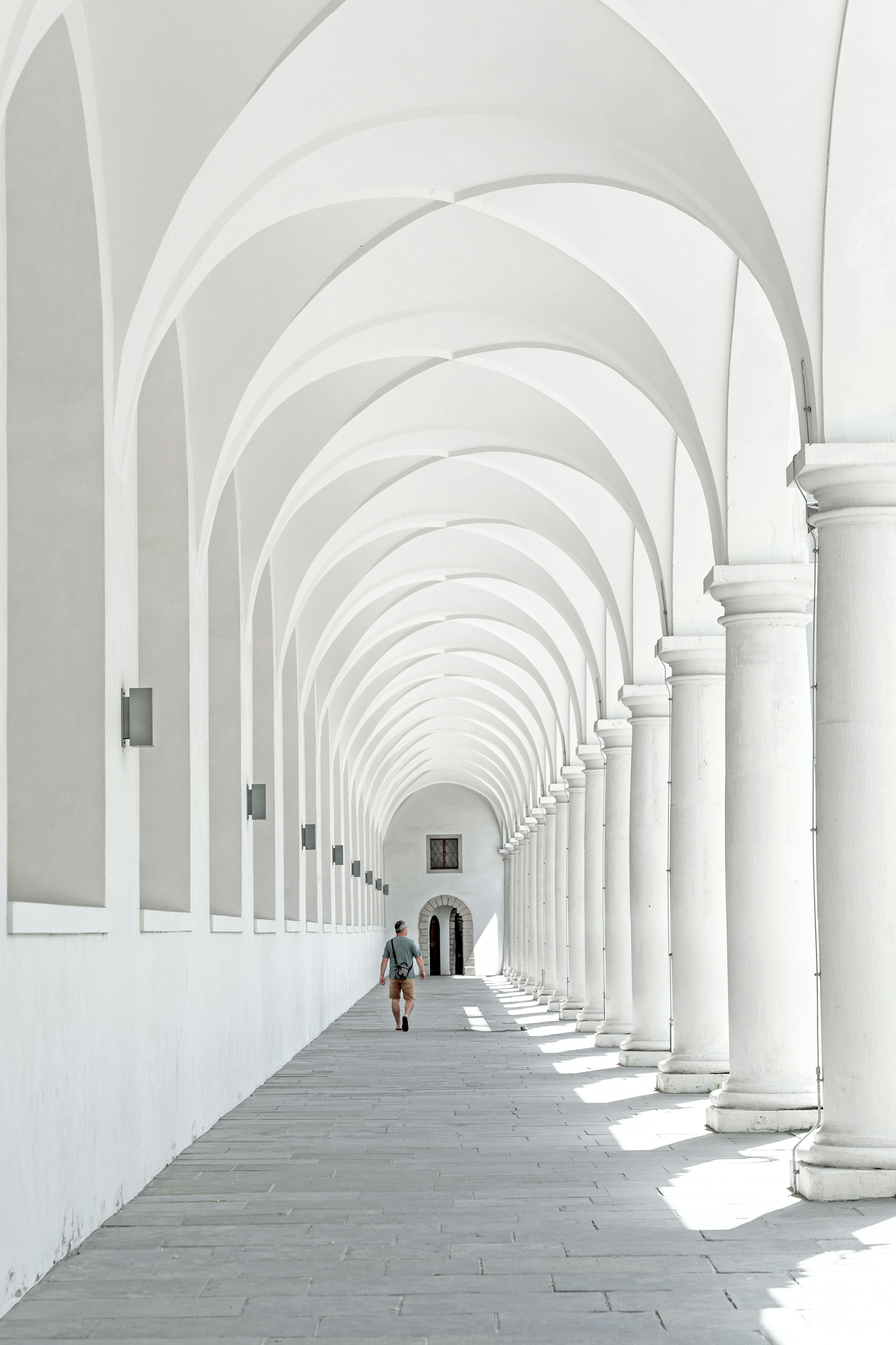 A person walks through the historic arched colonnade in Dresden, Germany, showcasing stunning architecture.