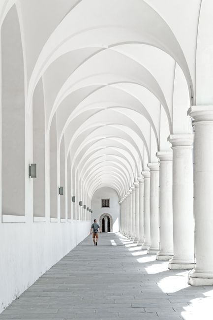 A person walks through the historic arched colonnade in Dresden, Germany, showcasing stunning architecture.