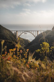 Beautiful view of Bixby Creek Bridge at sunset surrounded by coastal hills in Big Sur, California.
