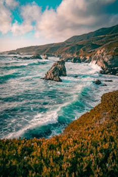 Breathtaking seascape of Big Sur's coastline with waves crashing against rocky shores under a vibrant sky.